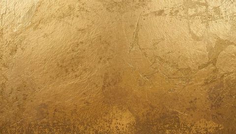 Glowing gold leaf texture revealing cracks, patina and metallic sheen luxury background