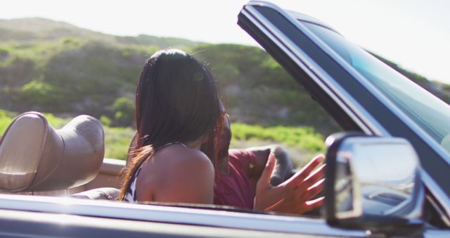 African american couple having fun while sitting in the convertible car on road. road trip travel and adventure concept