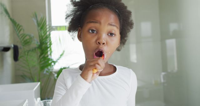 Image of african american girl brushing teeth in bathroom. Lilvestyle, daily hygiene and time at home.