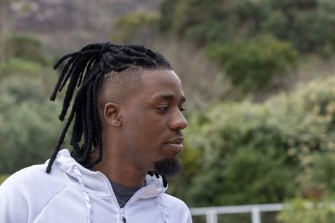 African american man with dreadlocks looking right in outdoor park wearing light hoodie