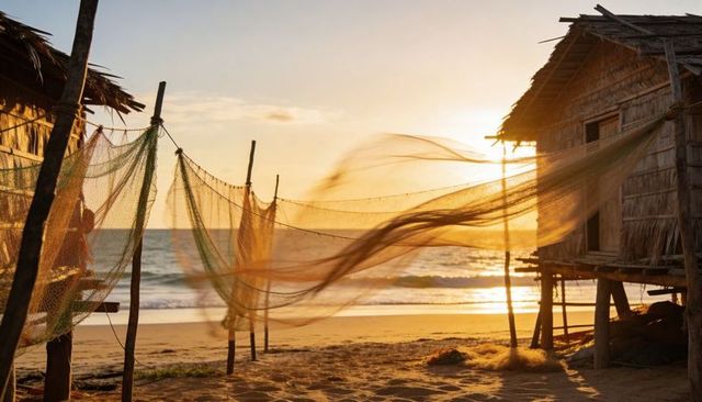 Golden-hour fishing nets billowing on sandy beach with stilted wooden hut and ocean waves