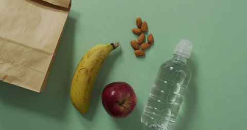Healthy School Lunch with Fruits and Water Bottle on Green Background