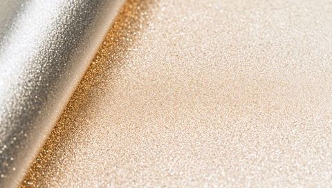 Rolled gold glitter catching light on sparkling metallic sheet for luxury backgrounds