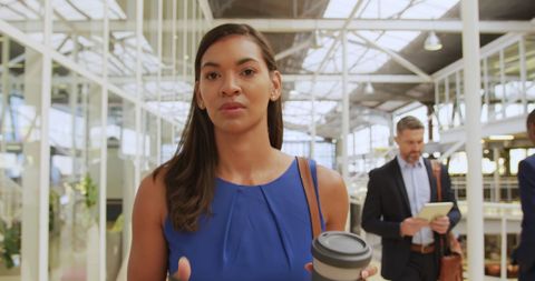Confident Businesswoman Walking with Coffee in Modern Office