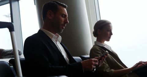 Businessman Texting On Phone in Airport Lounge with Luggage
