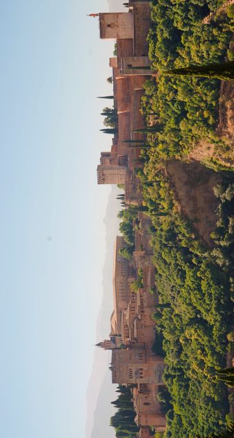 Impressive view of Alhambra fortress in Granada surrounded by greenery. Ideal for use in travel blogs, tourism websites, cultural heritage publications, and educational materials covering Spanish history and architecture.