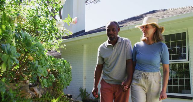 Senior couple enjoying a walk outside their modern home. Ideal for concepts like retirement, togetherness, healthy lifestyle, and enjoying nature. It portrays a peaceful, relaxed moment with natural surroundings, perfect for use in retirement planning, real estate, and health promotions.