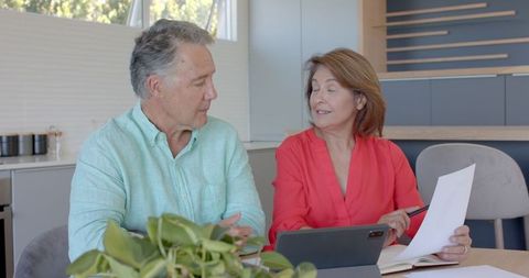 Senior Couple Reviewing Documents with Tablet in Modern Kitchen