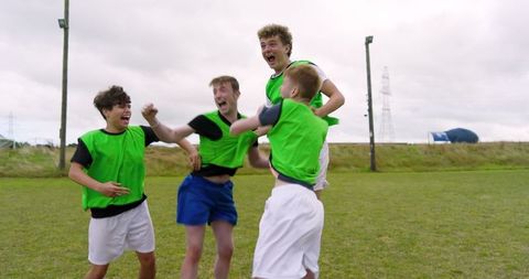 Energetic Teenage Team Celebrating Victory on Grassy Field