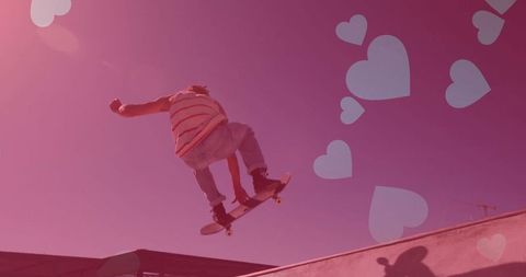 Skateboarder Performing Trick Against Pink Valentine's Day Background