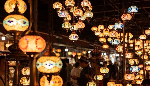 Hanging mosaic lanterns glowing and illuminating crowded bazaar aisles with warm light