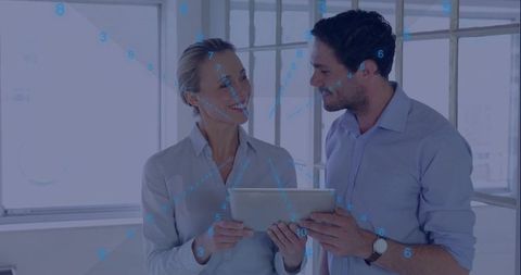 Business colleagues collaborating over tablet with digital data overlay in bright office