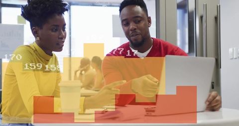 Two coworkers collaborating over laptop with colorful analytics overlay in modern office