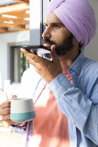 Man with lavender turban using smartphone at home