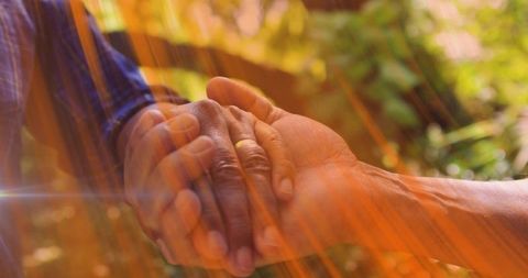 Elderly Couple Holding Hands in Sunlit Garden Showing Tenderness