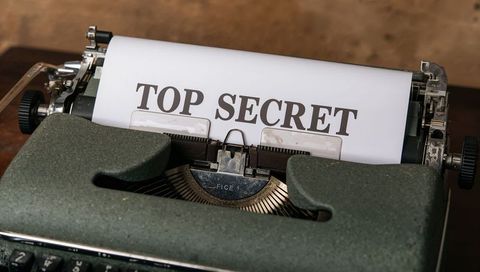 Vintage manual typewriter printing top secret document on weathered wooden desk