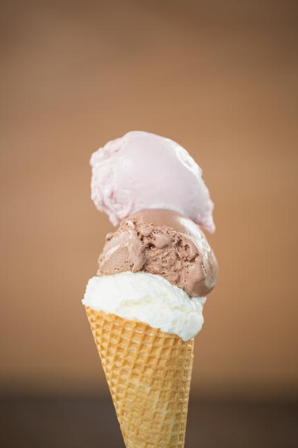 close-up of waffle cone with three different scoops of ice cream