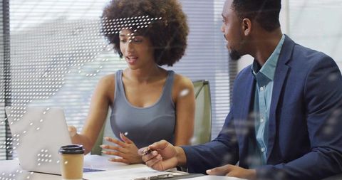 Young professionals collaborating at laptop in modern conference room during team meeting