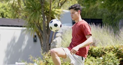 Young Man Practicing Soccer Skills in Garden