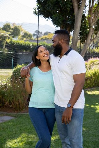 Diverse Couple Smiling Outdoors on Grassy Lawn