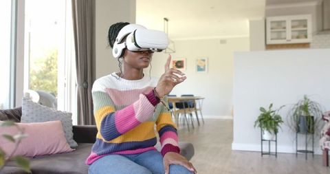 Woman Experiencing Virtual Reality at Home in Colorful Sweater