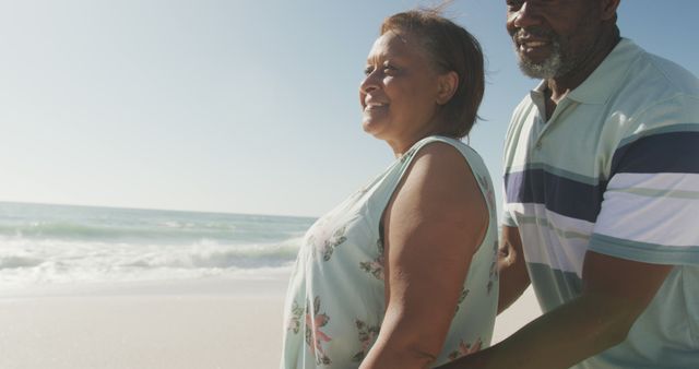 Senior couple is enjoying time together on the beach with ocean waves in the background. They are bonding, showing affection and happiness. Perfect for depicting themes of retirement, love, and travel.