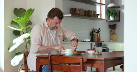 Senior Man Enjoying Avocado Toast in Stylish Modern Kitchen