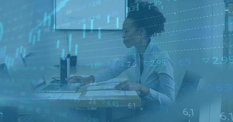 Businesswoman analyzing financial data on laptop with transparent stock charts overlay