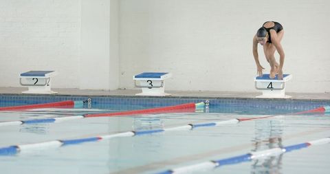 Female swimmer diving practice in indoor pool preparation