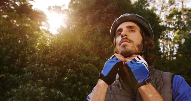 Cyclist Adjusting Helmet in Sunlit Forest - Download Free Stock Images Pikwizard.com