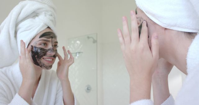 Woman Applying Face Mask While Looking in Bathroom Mirror - Download Free Stock Images Pikwizard.com