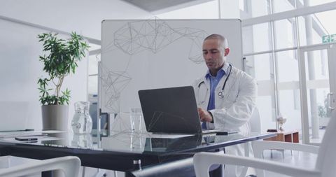Doctor Typing on Laptop at Modern Medical Office Table