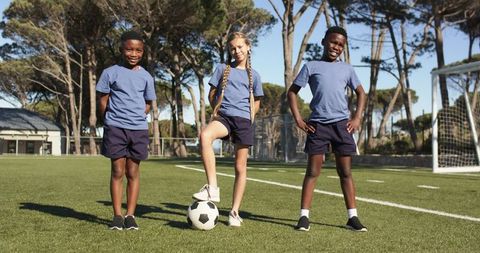 Youth soccer teammates posing on turf with ball and goal promoting teamwork and confidence