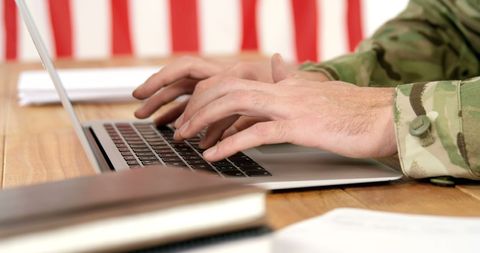 Military Personnel Engaging in Work on Laptop in Office Desk Setting