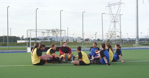 Diverse Female Athletes Huddling on Turf Hockey Field