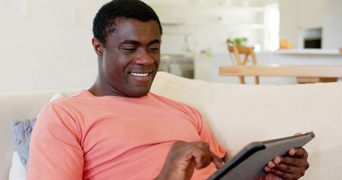 African american man relaxing on sofa using tablet at home