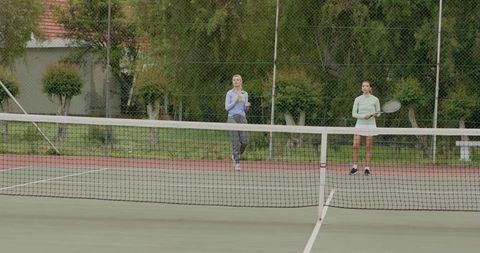 Two Women Practicing Casual Tennis on Outdoor Neighborhood Court Holding Racket and Water Bottle