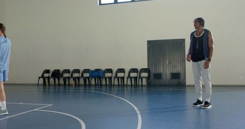 Coach Guiding Player in Indoor Basketball Training Session