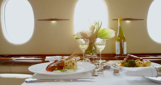 Table in private jet offers elegant dining with gourmet meal and wine. Fresh flowers enhance sophistication. Ideal for use in travel magazines, luxury lifestyle blogs, advertisements for high-end services, or content showcasing upscale dining experiences.