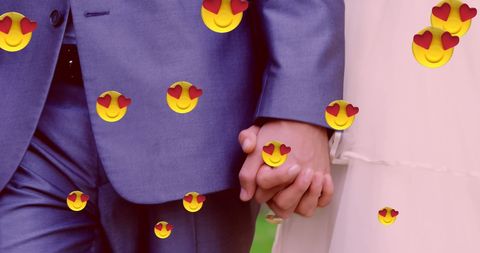 Newlyweds holding hands with floating heart eyes emojis