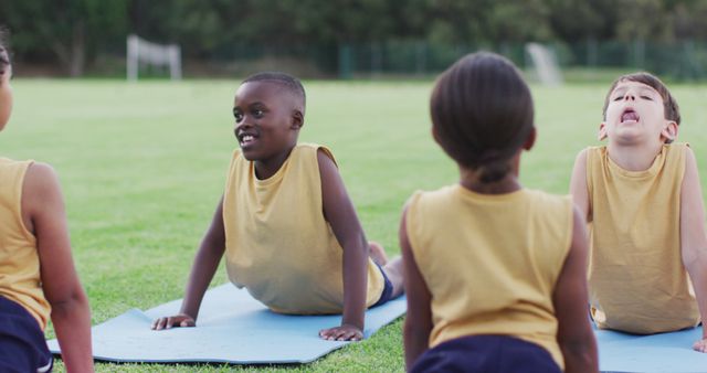 Diverse group of schoolchildren lying on mats meditating during yoga lesson outdoors. children at primary school in summer.