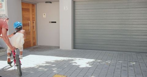 Father Teaching Daughter Bicycle Outside Urban Home
