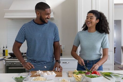 Cheerful couple preparing meal in modern kitchen