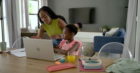 African american mother guiding daughter on laptop while homeschooling and learning together