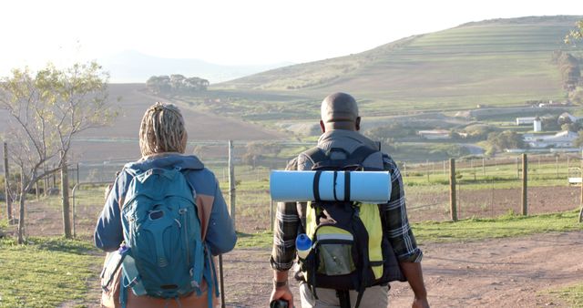Back view of happy senior african american couple walking with backpacks and looking on landscape. Retirement,relaxation, togetherness, senior lifestyle, unaltered, copy space.