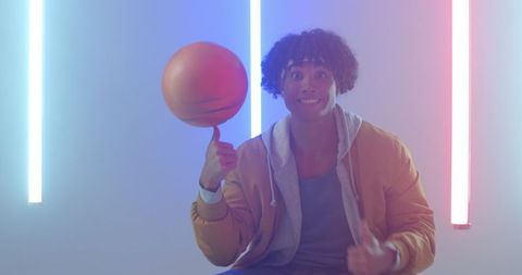 Energetic african american man spinning basketball under neon lights