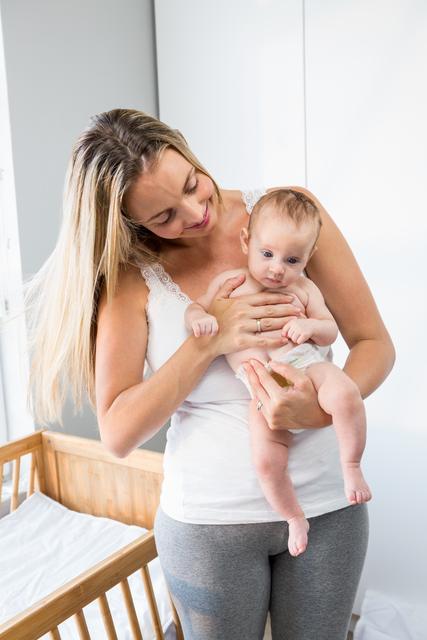 Mother holding her baby boy in a bright home environment, emphasizing warmth, bonding, and family love. This image can be used for parenting blogs, family health articles, and advertisements for baby products or maternity wear.