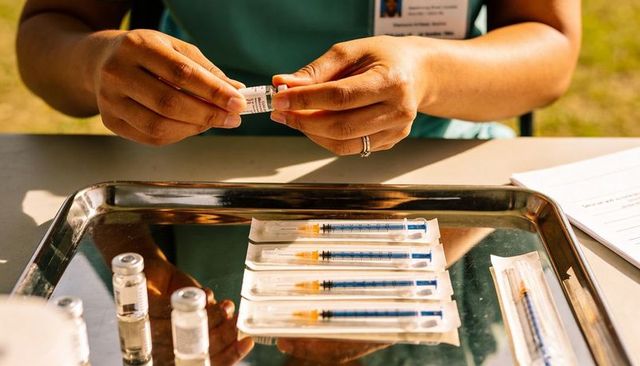 Preparing vaccine vials and syringes for outdoor immunization clinic on stainless tray