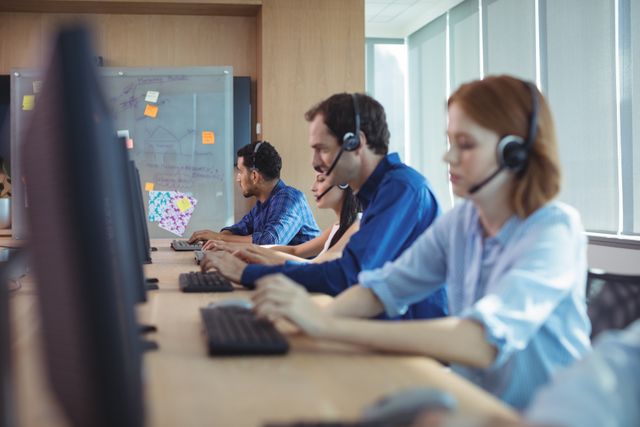 Employees focusing on work in a modern call center. Ideal for illustrating customer service, telecommunication, teamwork, and professional office environments. Suitable for business presentations, website imagery, and articles about workplace efficiency, customer support, and corporate communication.