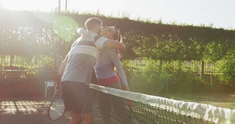 Caucasian Couple Embracing After Tennis Match Under Sunlight